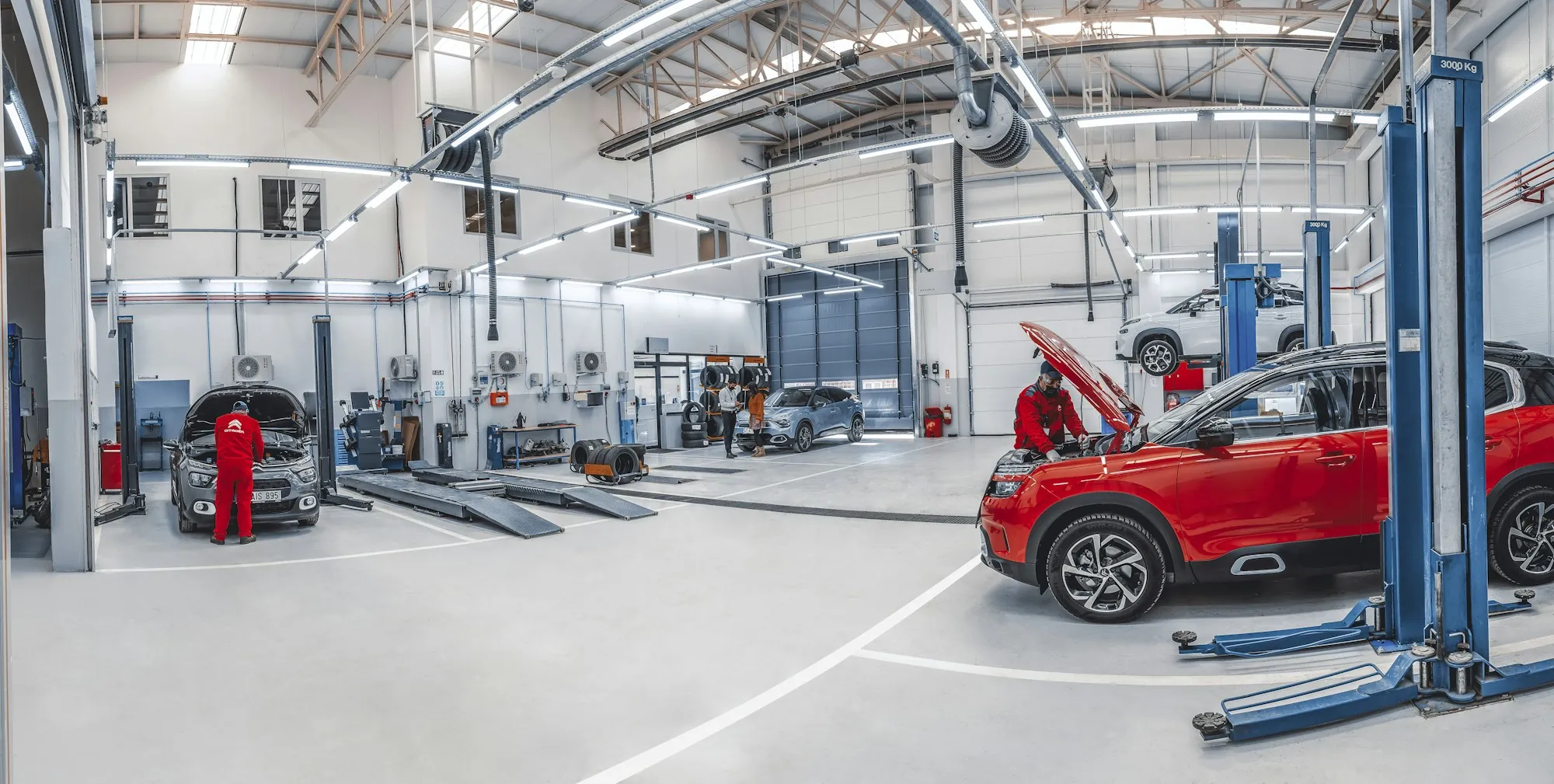 Mechanics working on cars in a bright automotive repair workshop