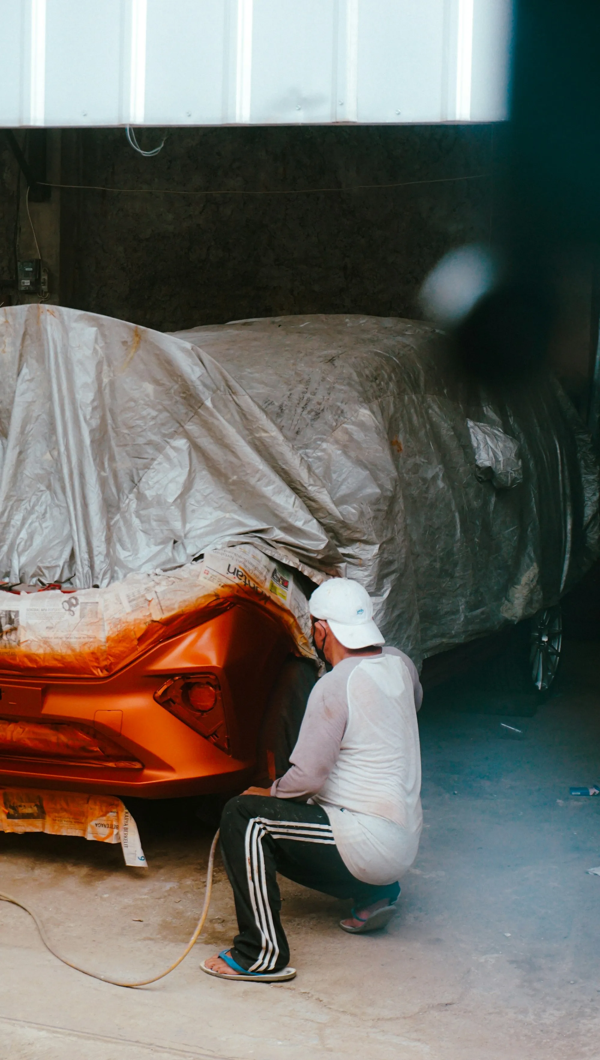 Technician masking a car body in a shop before painting